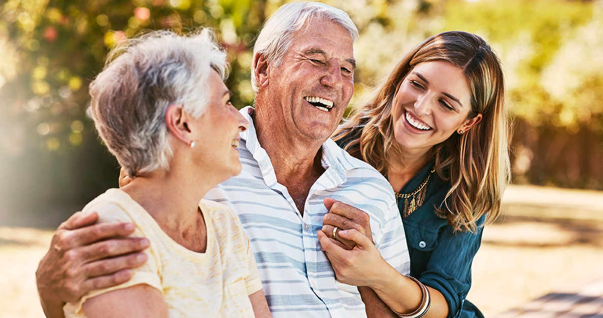 Une femme et ses parents qui profitent d'un moment joyeux dans les jardins de la résidence seniors Claricia